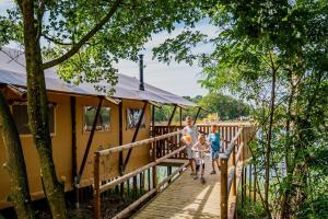 a bridge over the water with two children walking on it at Waterlodge 8 persons #WL02 in Maasbree