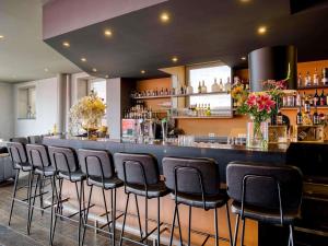 a bar with a row of stools in a restaurant at Mercure Hotel Amersfoort Centre in Amersfoort