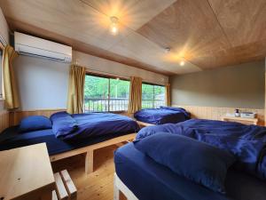 ein Zimmer mit drei Betten und einem Tisch in der Unterkunft michikusha in Maniwa