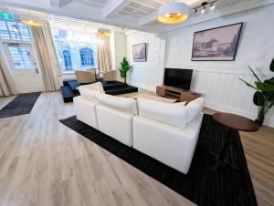 a living room with a white couch and a tv at Hotel Manoir Morgan in Quebec City