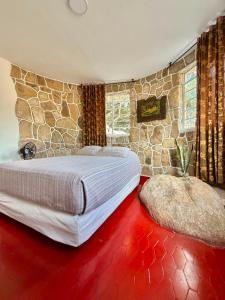 a bedroom with a large bed and a stone wall at Cabañas El Itali in Fusagasuga +49 photos