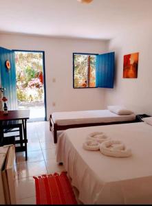 a bedroom with two beds and a desk and a window at Cajibá Imbassai in Imbassai
