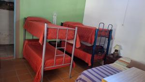 a room with two bunk beds with red sheets at Casa con bajada al rio in Villa Cura Brochero