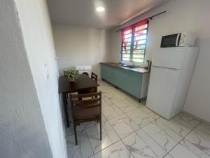 a kitchen with a refrigerator and a table and a desk at Appartement t2 in Matoury