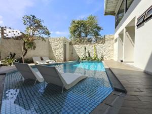 a swimming pool with two chairs next to a house at HŌM Coliving Bali in Kerobokan