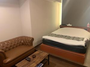 a room with a bed and a couch and a table at Rplus八千代 in Chiba