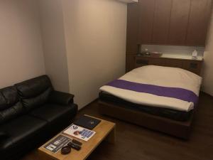 a small room with a bed and a couch at Rplus八千代 in Chiba