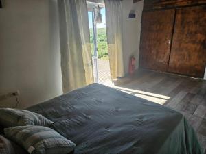 a bedroom with a bed and a large window at Vertiente escondida in Villa Yacanto