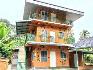 an orange building with a balcony on it at Fruits Garden Resort in Kotamangalam