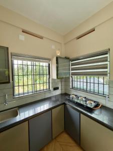 a kitchen with a counter and two windows in it at Fruits Garden Resort in Kotamangalam