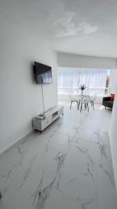 a living room with white marble floors and a tv at my house on the upper beach in Villas del Mar