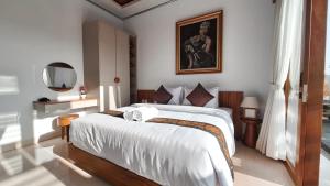 a bedroom with a bed with a picture on the wall at Villa Kasuri Bali in Blahbatu