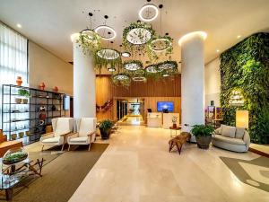 a large lobby with white chairs and plants at Grand Mercure Itaim Bibi | Premium & Luxury Flat in São Paulo