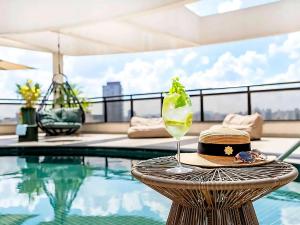 a hat and a drink on a table next to a pool at Grand Mercure Itaim Bibi | Premium & Luxury Flat in São Paulo