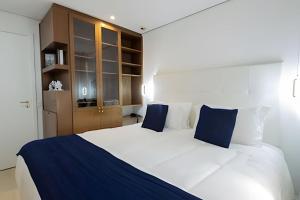 a bedroom with a large white bed with blue pillows at Grand Mercure Itaim Bibi | Premium & Luxury Flat in São Paulo +42 photos