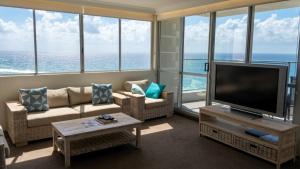 a living room with a flat screen tv and large windows at The Penthouses Apartments in Gold Coast