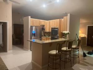 a kitchen with a counter with stools and a refrigerator at Hutchinson River House in Fort Pierce
