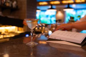 a drink and a book on a bar with a book at Hotel Resol Trinity Kyoto in Kyoto