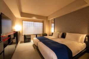 a bedroom with a large bed and a flat screen tv at Hotel Resol Trinity Kyoto in Kyoto