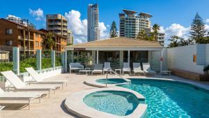 a swimming pool with lounge chairs and a building at The Penthouses Apartments in Gold Coast
