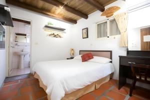 a bedroom with a white bed and a bathroom at 任我行民宿 in Jincheng
