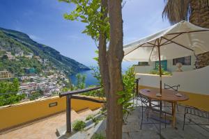 a table and chair under an umbrella on the balcony of a house at Casa Hellen Positano center in Positano