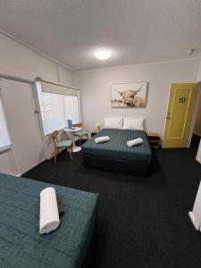 a bedroom with two beds and a yellow door at Manning River Motel in Taree