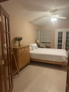 a bedroom with a bed and a dresser and a ceiling fan at Hutchinson River House in Fort Pierce