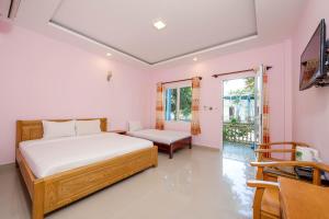 a bedroom with a bed and a couch and a tv at Trương Nhi Bungalow in Phú Quốc
