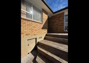 a building with wooden steps in front of a brick building at Private 2-Bedroom Suite in 3-Bedroom House in Auckland