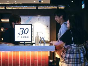 a group of people standing around a counter at 30 PIECES Namba in Osaka