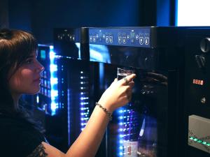 a woman is putting a glass in a machine at 30 PIECES Namba in Osaka