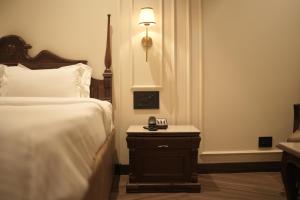 a bedroom with a bed and a nightstand with a clock on it at Regent Park Hotel in Jalandhar