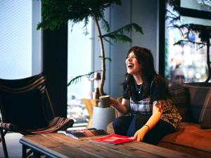 a woman sitting on a couch holding a coffee cup at 30 PIECES Namba in Osaka