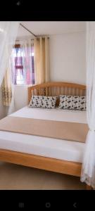 a bedroom with a large bed with a wooden frame at Delhi Gardens Hotel in Fort Portal