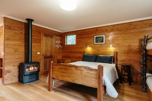 a bedroom with a bed and a woodburning stove at Cradle Highlander in Cradle Mountain