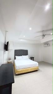 a white bedroom with a bed and a table and a ceiling at Sergi's Resort and Hotel in Palompon