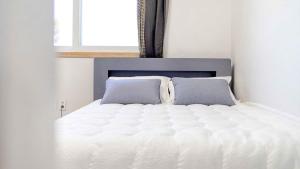 a white bed with two pillows in a bedroom at Goseong Pinetree Pension in Goseong