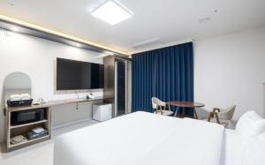 a hotel room with a bed and a flat screen tv at Brown Dot Hotel Daecheon Beach, Boryeong in Boryeong