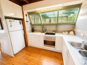 a kitchen with a white refrigerator and a sink at Cottage on the Lake - peaceful Burrill Lake escape in Burrill Lake