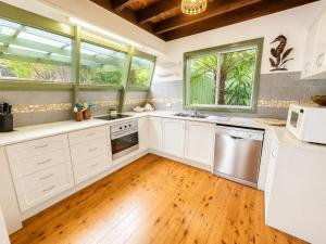 a kitchen with white cabinets and a wooden floor at Cottage on the Lake - peaceful Burrill Lake escape in Burrill Lake