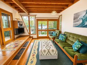 a living room with a green couch and a rug at Cottage on the Lake - peaceful Burrill Lake escape in Burrill Lake