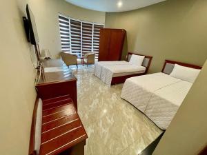 a hotel room with two beds and a television at Nam Phong Hotel & Coffee in Cái Rồng +1 photo