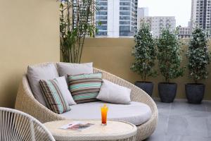 a wicker chair with pillows on a balcony with plants at City Garden Suites Manila in Manila