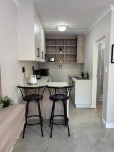 a small kitchen with two bar stools and a counter at The Red Couch Accommodation in Tsumeb