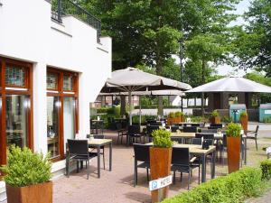 a restaurant with tables and chairs and umbrellas at Hotel Huys van Heusden in Asten