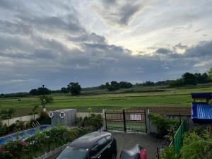a car parked in front of a fence with a field at BalaiBesa Transient House in Lingayen