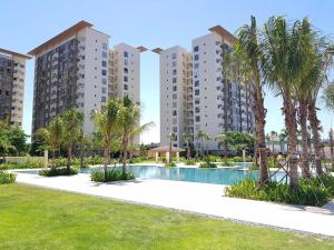 a resort with a swimming pool and palm trees at Alabang Staycation by East Bay Residence in Sampong
