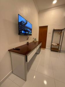 a room with a desk with a tv on the wall at Bunohan Villa Roomstay in Tumpat