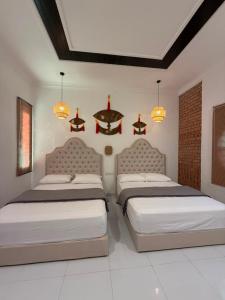 a bedroom with two beds and two chandeliers at Bunohan Villa Roomstay in Tumpat
